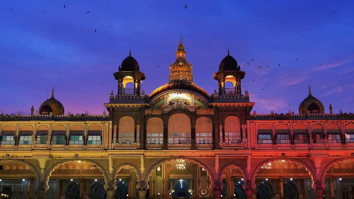 Stunning view of Mysore Palace during sunset with vibrant lighting and sky.