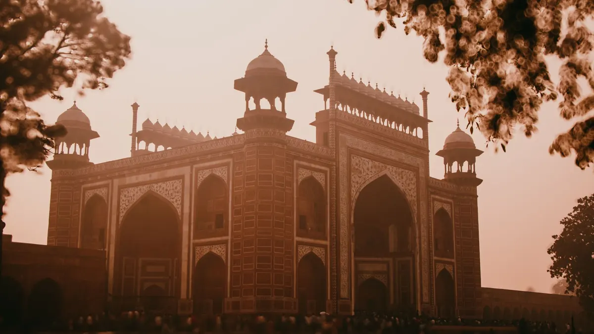 The majestic entry gate to the Taj Mahal in Agra, India, captured at sunset, exudes historical charm.