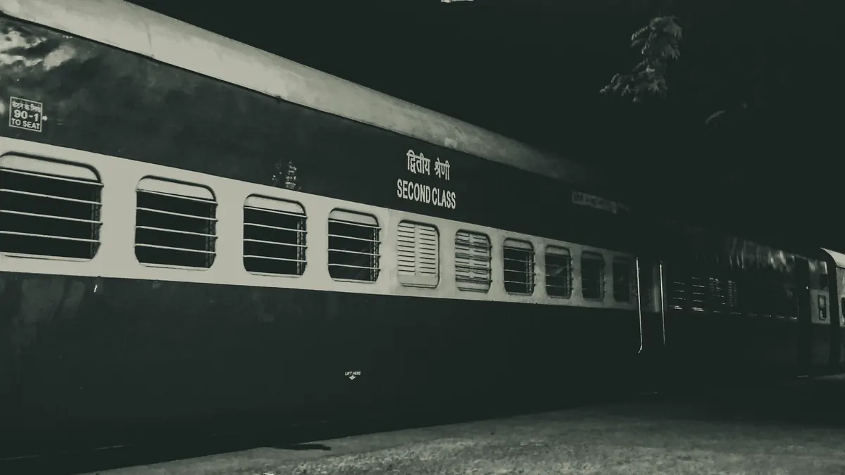 Night photo of a second class train parked outdoors under a station roof.