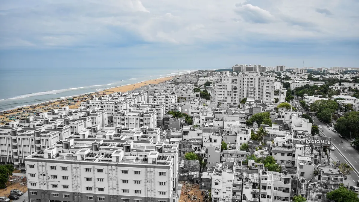 Aerial view of Chennai's urban landscape with Marina Beach in the background.