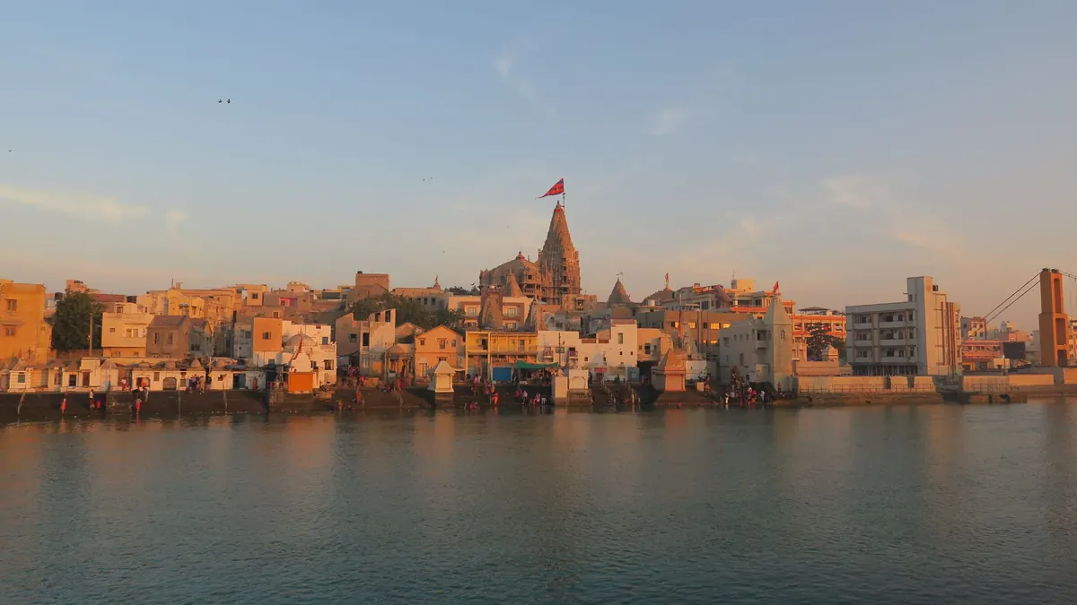 View of the historic Dwarka city and temple by the river at sunset, capturing its architectural beauty.