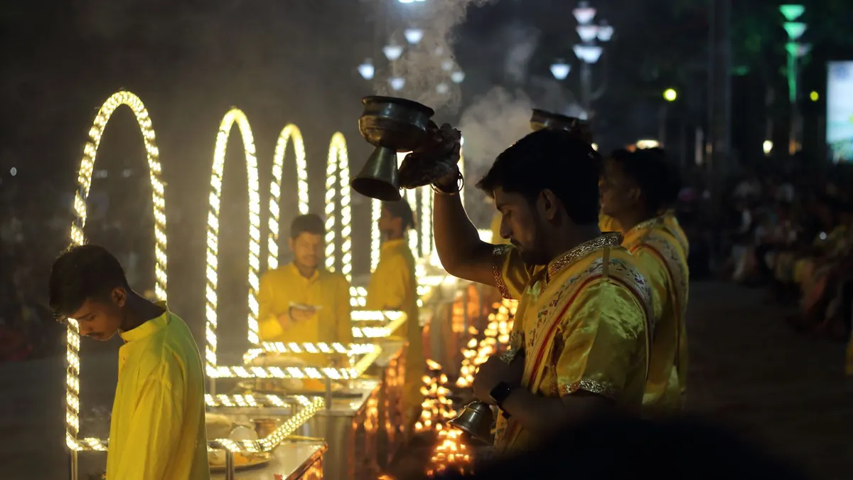 Devotees perform an aarti ceremony with lit flames on the Ganges River, celebrating Indian culture.
