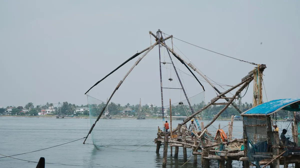 Scenic view of Chinese fishing nets in Kochi, Kerala with fishermen working on the shore.