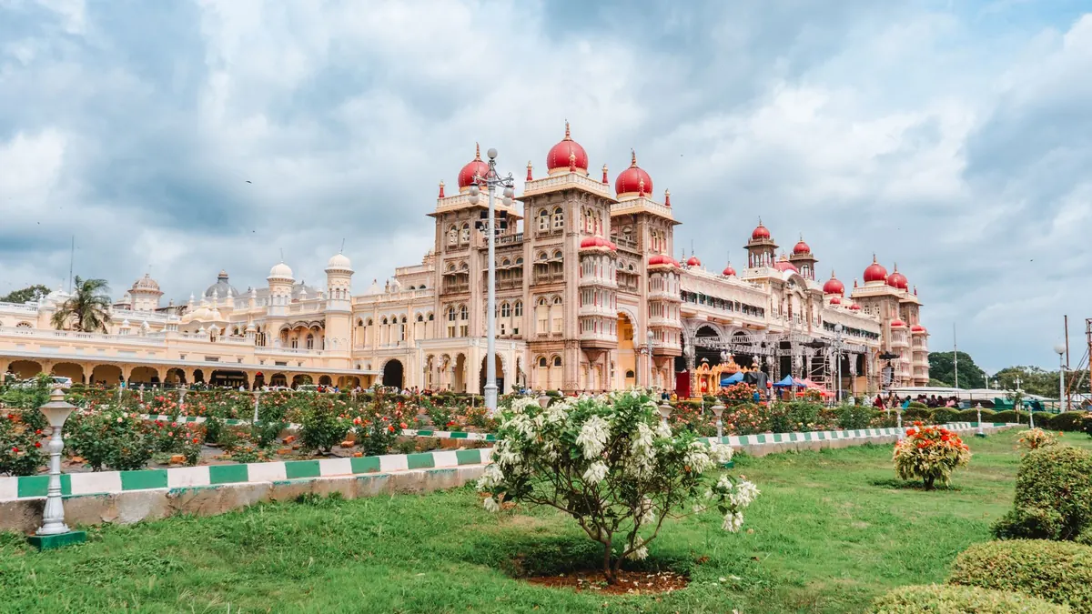 Stunning view of Mysore Palace in Karnataka, showcasing its ornate architecture and lush gardens under a cloudy sky.
