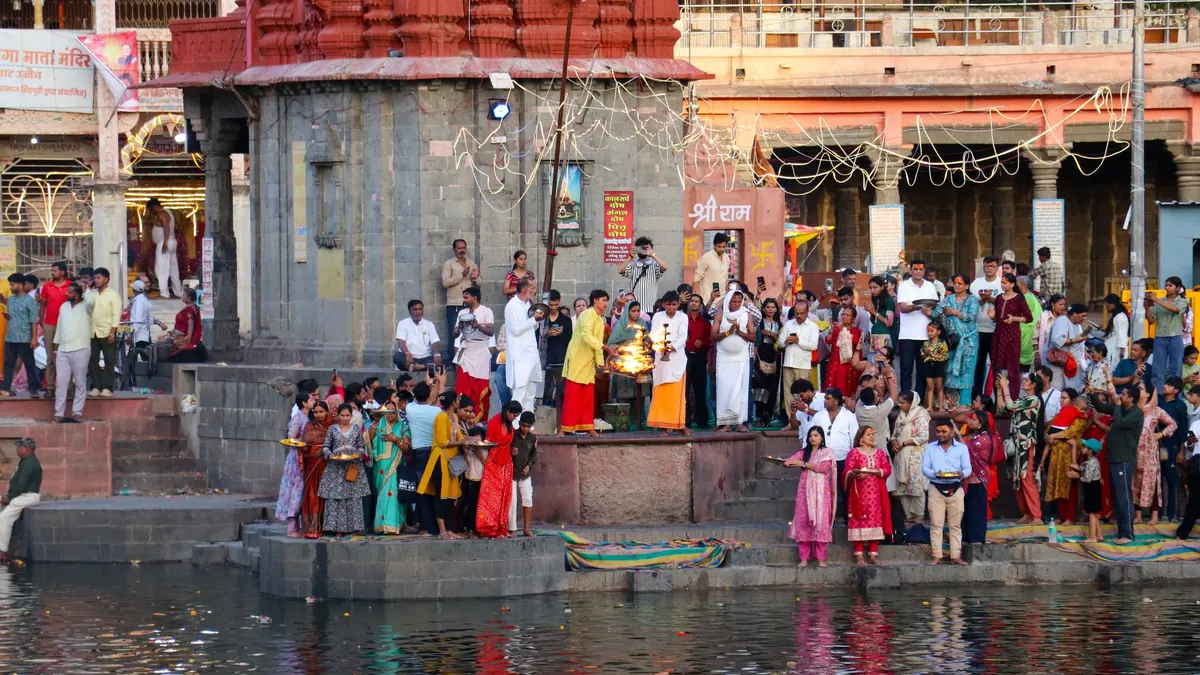 A vibrant spiritual gathering for Aarti at a temple ghat in Ujjain, India surrounded by devotees during sunset.