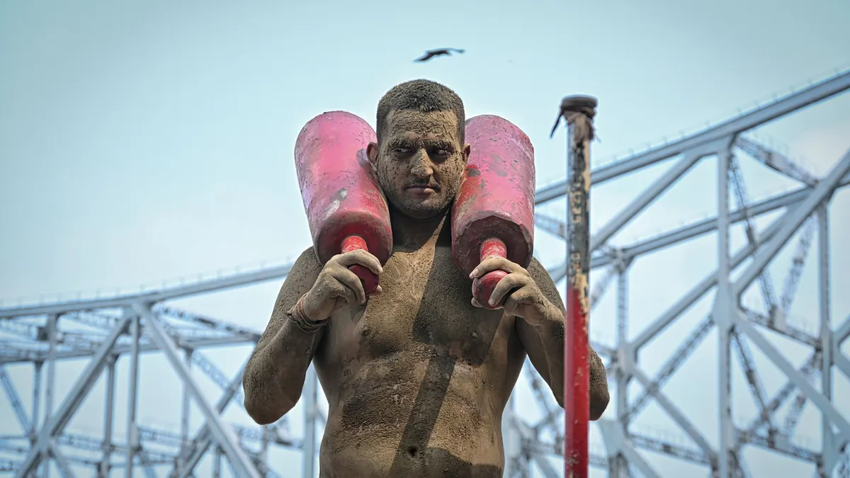A mud-covered wrestler practices under the iconic Howrah Bridge in Kolkata, India.