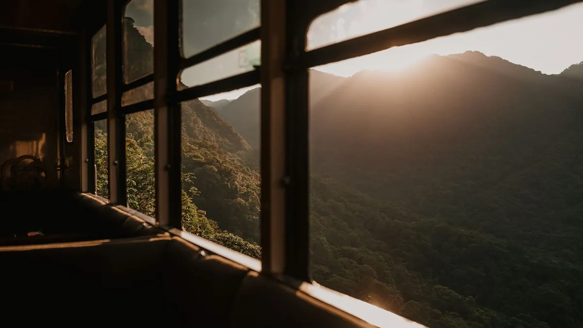 A serene view of mountains from a train during sunset, showcasing nature's beauty.