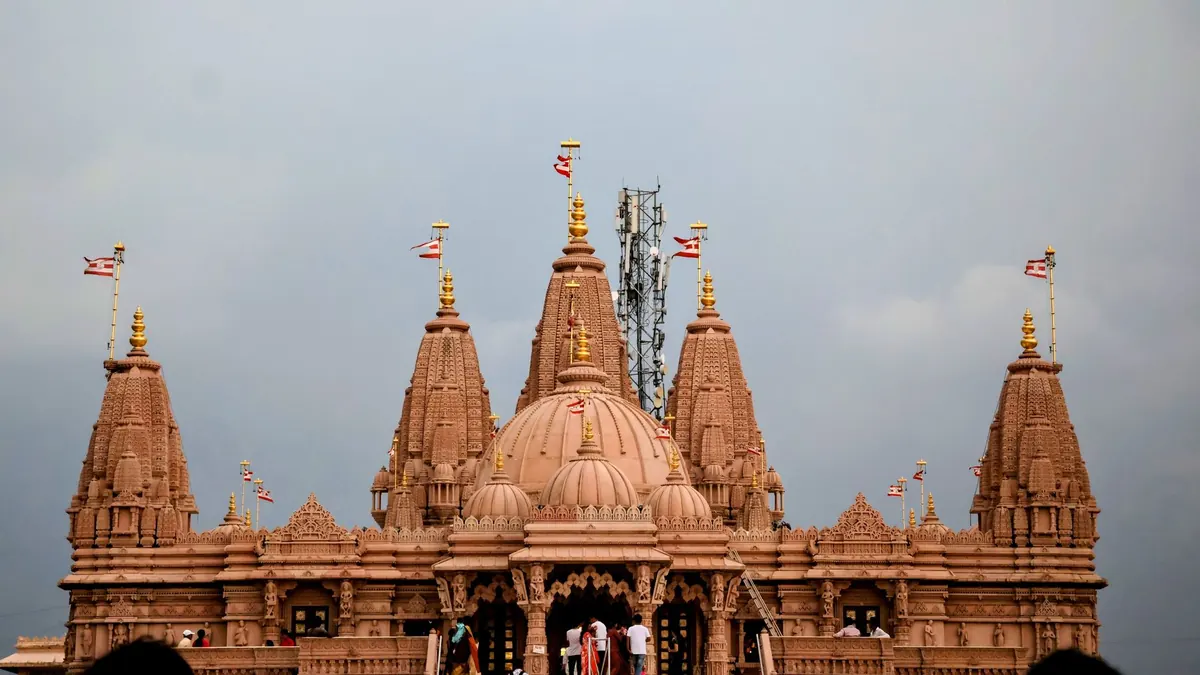 Majestic Swaminarayan Temple architecture against a cloudy sky, highlighting cultural heritage.