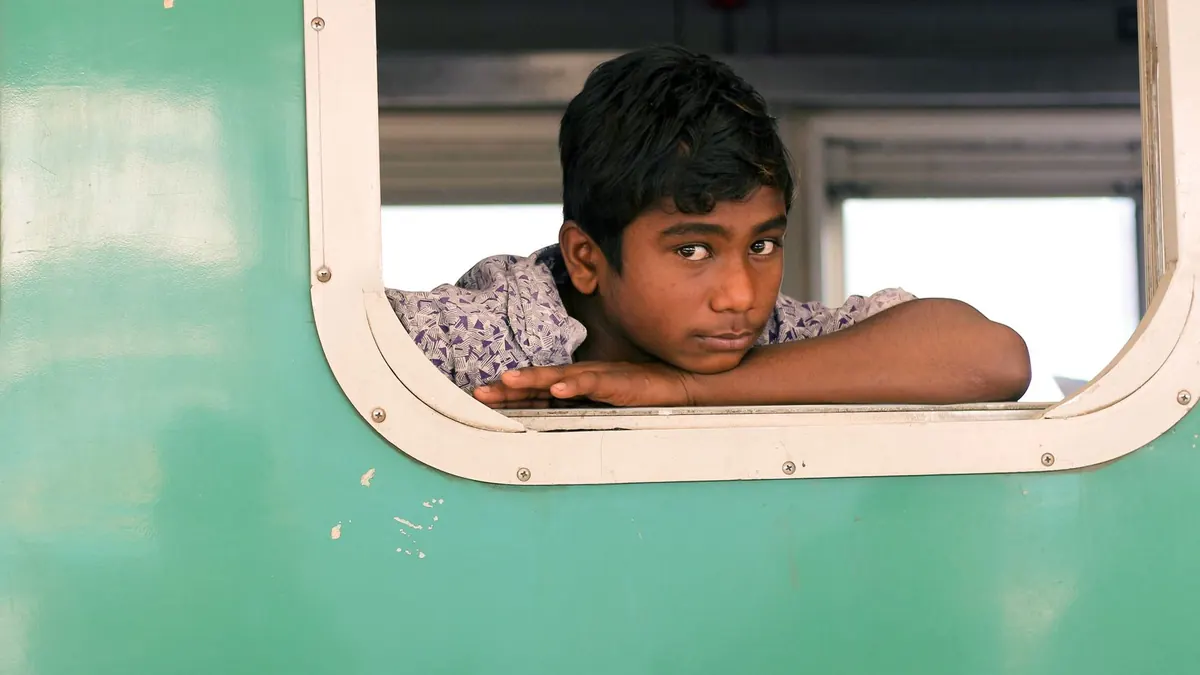 A young boy gazes from a train window, evoking the essence of youthful travel and adventure.