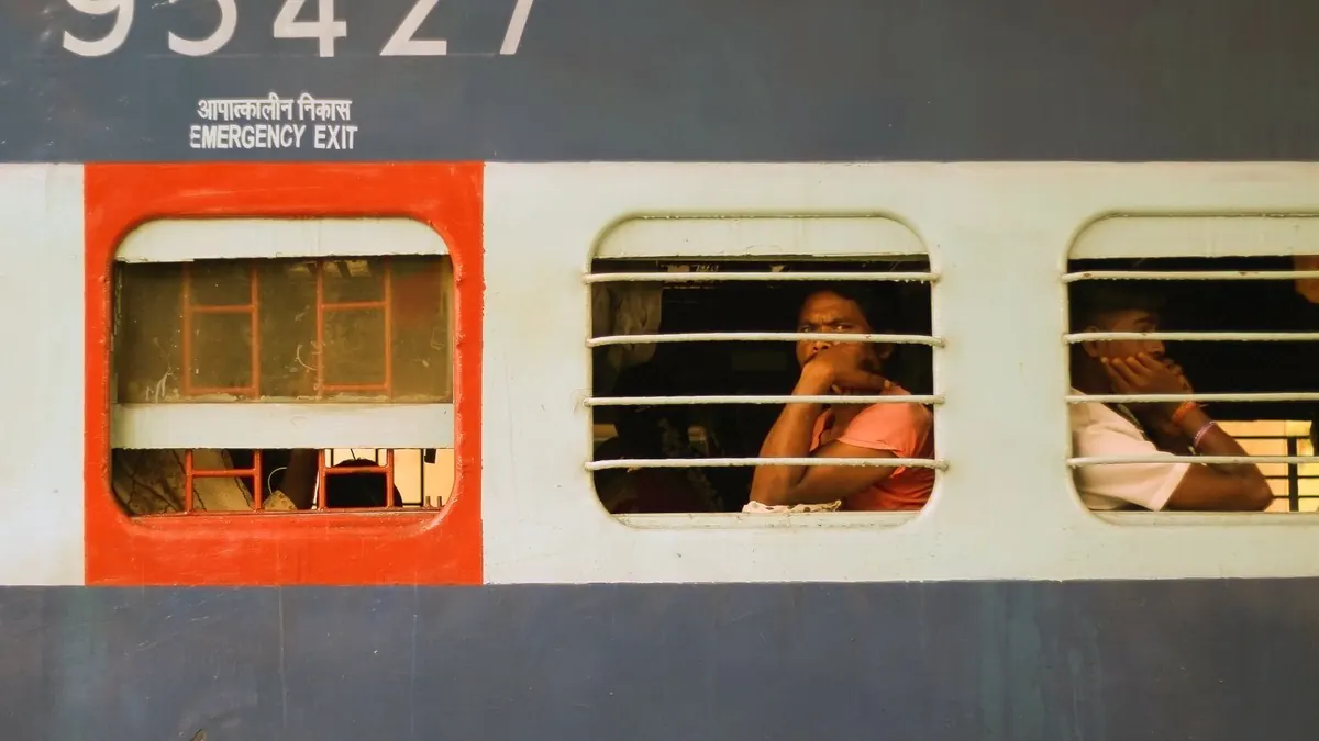 Travelers look out from a train window in India, capturing a moment of public transit life.