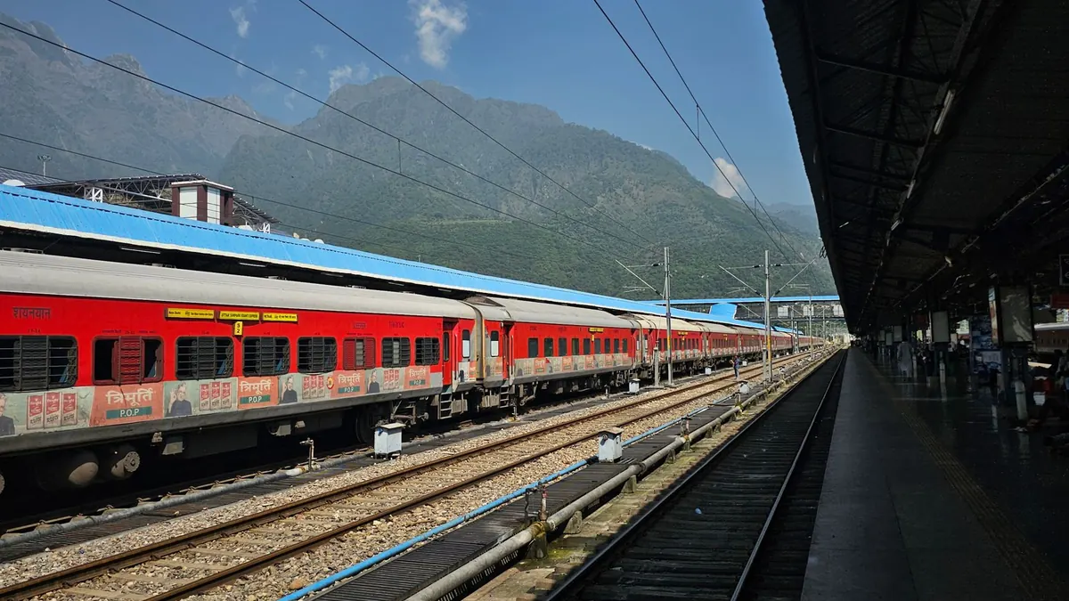 A vibrant red train at an outdoor station with scenic mountain backdrop, ideal for travel themes.