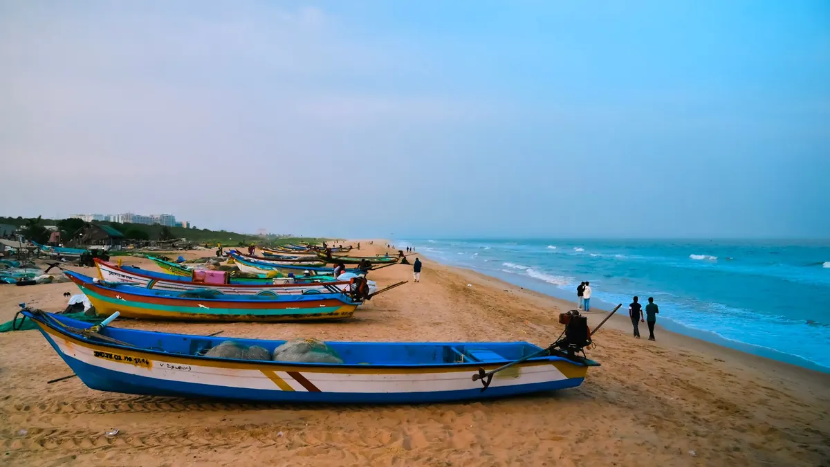 Colorful fishing boats on the sandy beach at sunrise in Chennai, India.